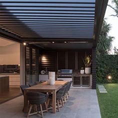 an outdoor kitchen and dining area is lit up at night with lights on the table