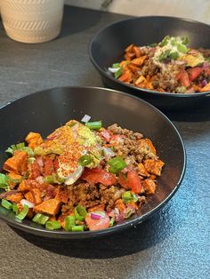 two black bowls filled with food on top of a table