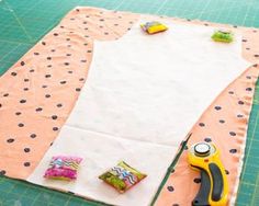 a pair of scissors and some fabric sitting on a cutting mat next to sewing supplies