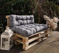 a couch made out of wooden pallets sitting on top of a deck next to a lantern