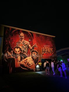 people standing in front of a building with a large mural on it's side