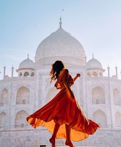 a woman in an orange dress is walking near the tajwa mosque, india