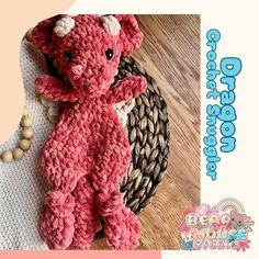 a pink crocheted teddy bear sitting on top of a wooden floor next to a basket