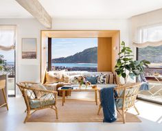 a living room filled with furniture and a large window overlooking the ocean on a sunny day