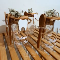 three clear glasses with wooden spoons and flowers in them