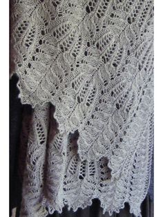 a white crocheted shawl hanging on a wall