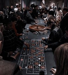 a large group of people sitting around a black table with numbers and dice on it