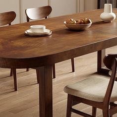 a wooden table with two chairs and a bowl of fruit on the dining room table