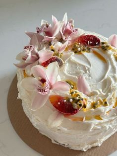 a cake with white frosting and pink flowers on top, sitting on a plate