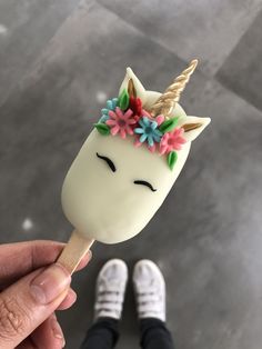 a hand holding a white and pink ice cream with a unicorn horn on it's head