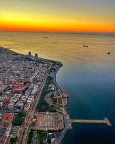 an aerial view of the city and ocean at sunset