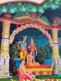 a man sitting on top of a bed in front of a colorful structure with statues