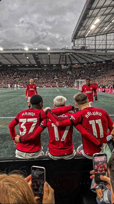 a group of men standing on top of a soccer field in front of a crowd