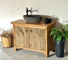 a bathroom sink sitting on top of a wooden cabinet next to a potted plant