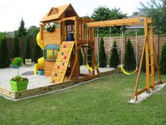 a wooden swing set in the backyard with a slide and swings for children to play on