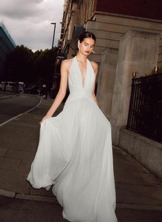 a woman in a white dress is walking down the street