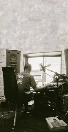 a man sitting at a desk in front of a microphone and sound equipment on the floor