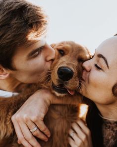 a man and woman kissing with a dog in front of the camera on a sunny day