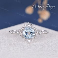 an engagement ring with a blue topazte surrounded by white diamonds and filigrees