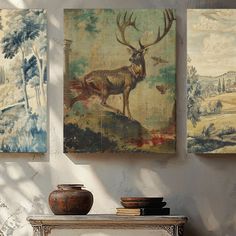 three paintings hang on the wall next to a table with two vases and an animal