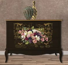 an ornate dresser with flowers painted on the front and sides, along with a gold vase