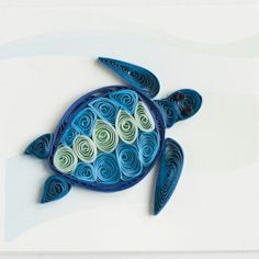 a blue and green turtle made out of rolled up paper on top of a white surface