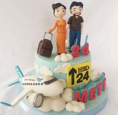 a cake with two people standing on top of it that has a plane and luggage