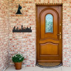 a wooden door sitting on the side of a brick wall next to a potted plant