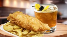 fish and chips on a plate next to a drink