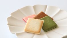 three different colored cookies on a white plate