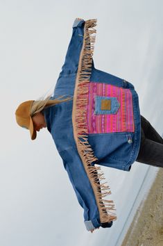 a woman wearing a jean jacket with fringes on it