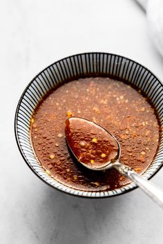 a spoon in a bowl filled with soup on top of a white countertop next to a napkin