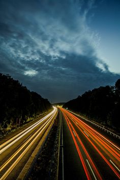 long exposure photograph of highway at night with light streaks on the road and trees in the background