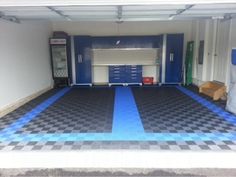 an empty garage with checkered floor and blue cabinets