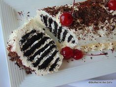 a piece of cake on a white plate with cherries and chocolate shavings