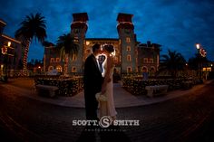 a bride and groom standing in front of a building at night