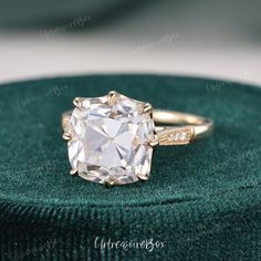 an old - fashioned diamond ring sits on a green velvet cushion, with the center stone surrounded by small diamonds