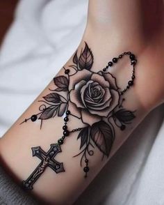 a woman's foot with a cross and rose tattoo on it