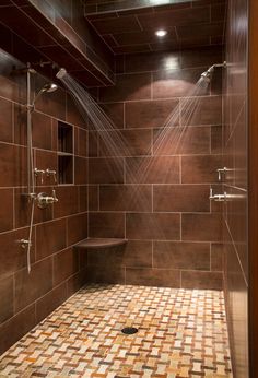 a bathroom with tiled walls and flooring in brown tones, including the shower head