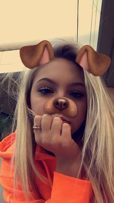 a girl with long blonde hair wearing an orange hoodie and dog ears on her head