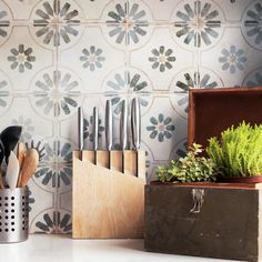 kitchen utensils are sitting on a counter next to a box with plants in it