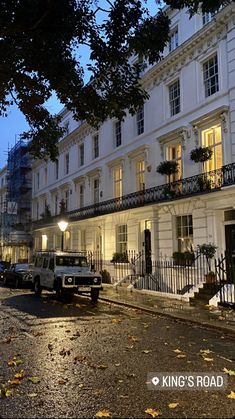 a street with cars parked on the side of it at night in front of a white building