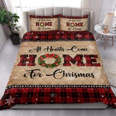 a bed covered in plaid and red comforter with christmas decorations on it, next to a window