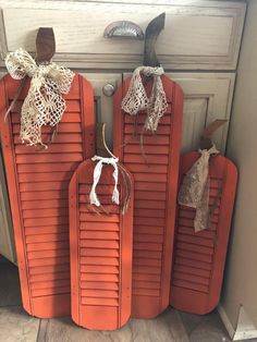 three red wooden doors with white lace on them and two bags hanging from the handles