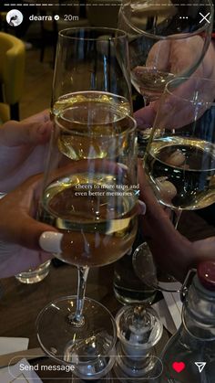 several glasses of wine are sitting on a table with people holding their hands over them