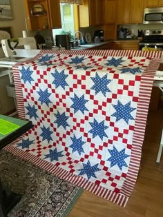 an american flag quilt hanging on a kitchen counter top in the middle of a wooden floor