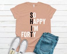 a t - shirt that says so happy i'm forty on it next to jeans and sneakers