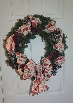 a wreath with pine cones and bows hanging on a door handle, decorated with red and white fabric