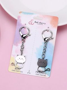 two key chains with cats on them sitting next to each other in front of a plate