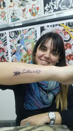 a woman sitting at a table with a tattoo on her arm that reads, believe